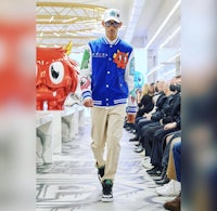 a man in a blue jacket walks down the runway