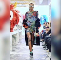 a woman in a colorful dress walks down a runway