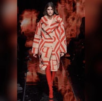 a model walks down the runway in a red coat and red leggings