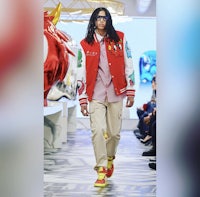 a man with dreadlocks walking down a runway