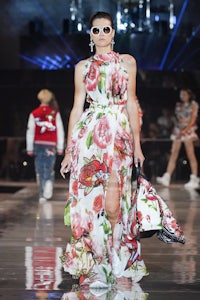 a model walks down the runway in a floral dress
